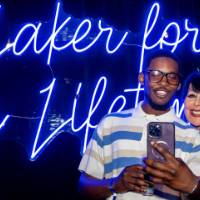 Philly poses with a grad taking selfie in front of Laker for a Lifetime sign